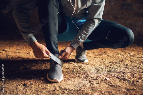 Bild auf Leinwand Close up of young active sportive runner man in sportswear tying his velcro shoe outside