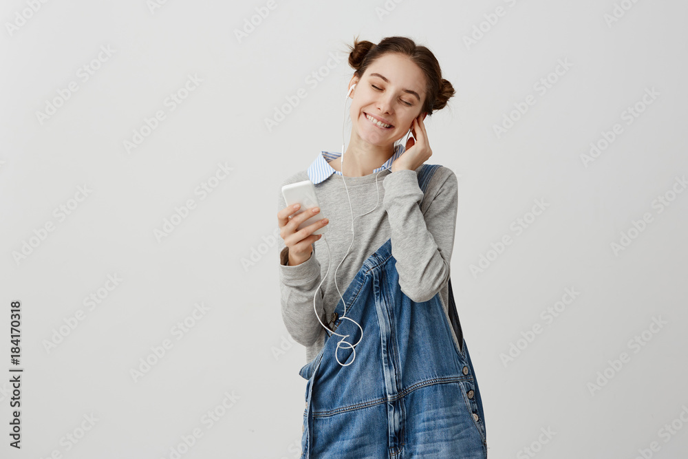 Portrait of glad delighted girl putting earphones taking enjoying merriment alone with music. Cute woman closing eyes in pleasure after getting compliments from husband. Human emotions Portrait of glad delighted girl putting earphones taking enjoying merriment alone with music. Cute woman closing eyes in pleasure after getting compliments from husband. Human emotions