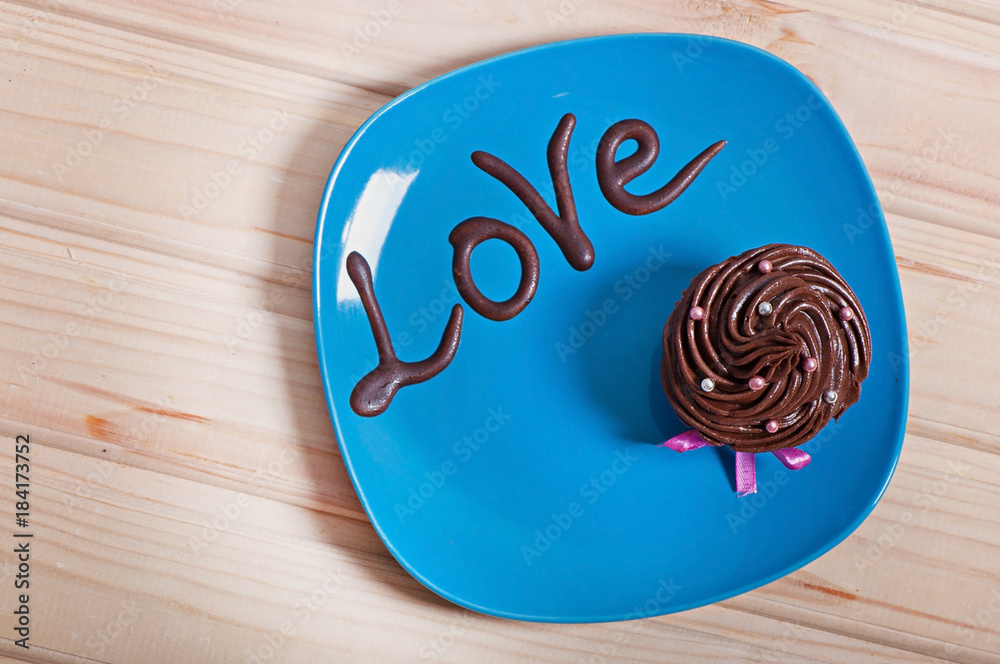 Chocolate cake with creamy cream on a blue plate, with a chocolate inscription love. Valentine's Day Chocolate cake with creamy cream on a blue plate, with a chocolate inscription love. Valentine's Day