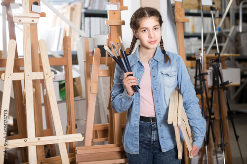 Teen girl holding supplies for painting in hands in art department
