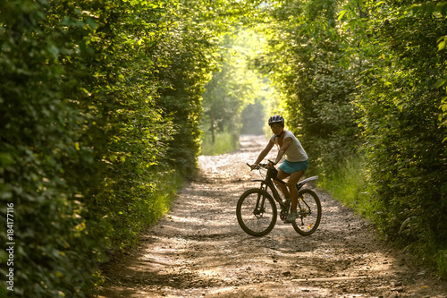 Woman rides bicycle in the beautiful green forest