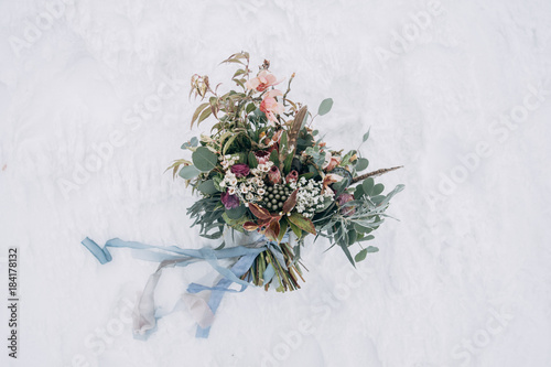 Wedding bouquet with blue and grey ribbons on the snow