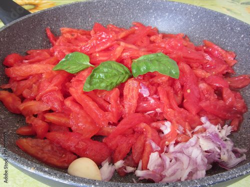 Cooking homemade tomato sauce using fresh summer tomatoes, onion, garlic and basil. Italian recipe