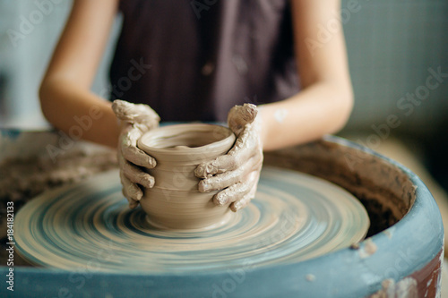 Obraz na plátne Hands of young potter, close up hands made cup on pottery wheel