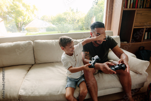 Father and son having fun playing video games at home