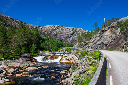 Beautiful view on the mountain river near the road, against the woody mountains, originating from a thawing glacier. the beginning famous of waterfall Langfossen, Norway. photo