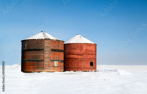 old red grain bins on a farm in Saskatchewan winter © Amy