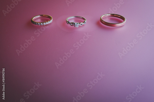 Gold and silver wedding rings on pink reflection