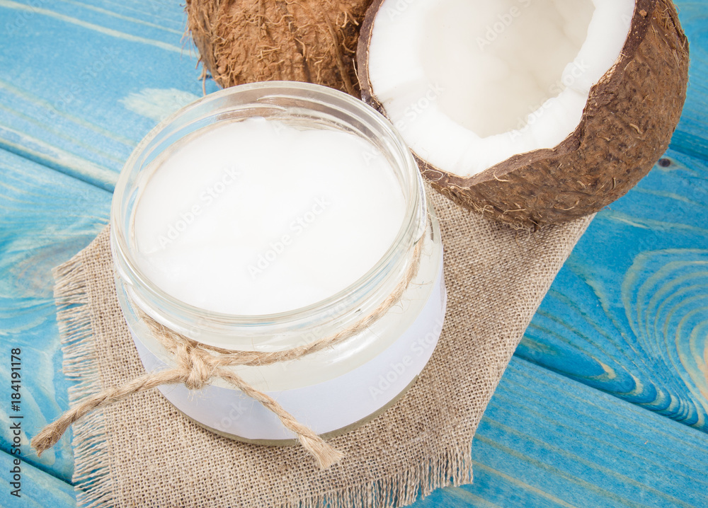 Coconut oil and fresh coconuts on a wooden table. Coconut oil and fresh coconuts on a wooden table.