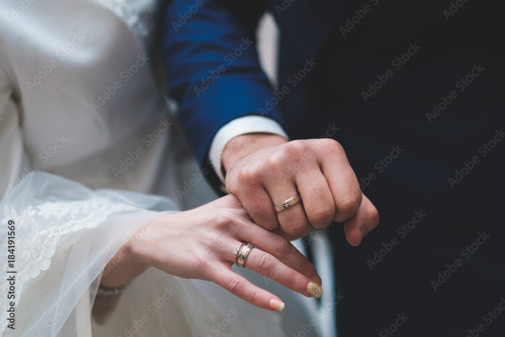 Gold and silver wedding rings on couple;s hands