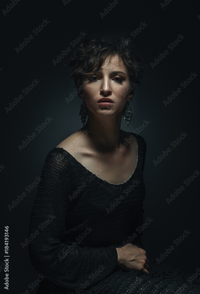 portrait in low key beautiful adult woman sitting on a chair wearing a knitted dress emotional portrait portrait in low key beautiful adult woman sitting on a chair wearing a knitted dress emotional portrait