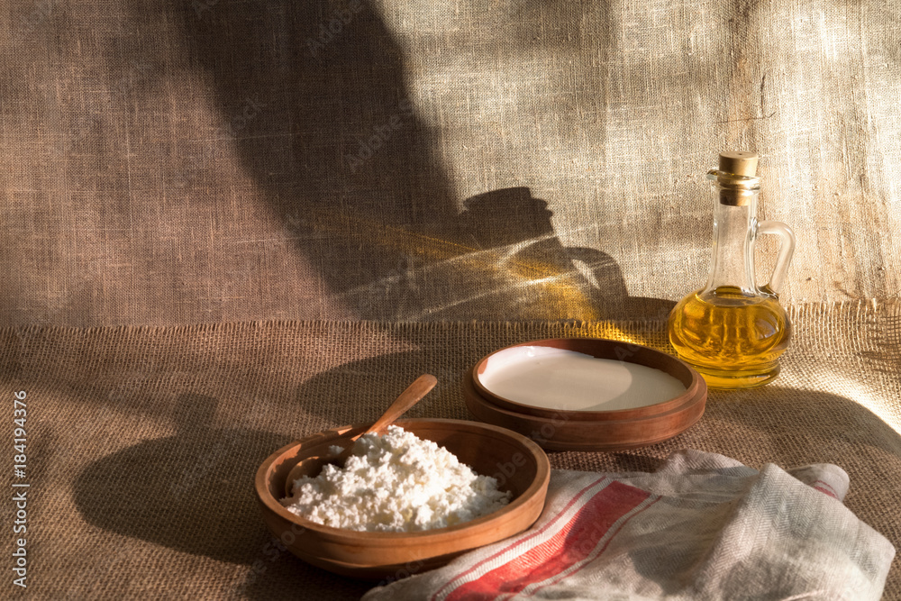 Fototapeta premium cottage curd and sour cream in wooden plate on a linen tablecloth and place for text