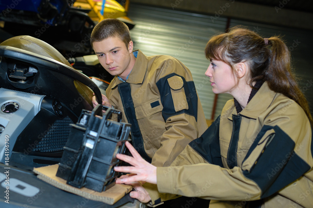 Obraz premium mechanics changing battery of jetski in garage