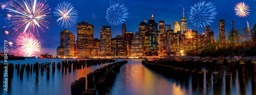 Sparkling celebration fireworks New York City Manhattan skyline with skyscrapers over Hudson River illuminated lights at dusk after sunset.