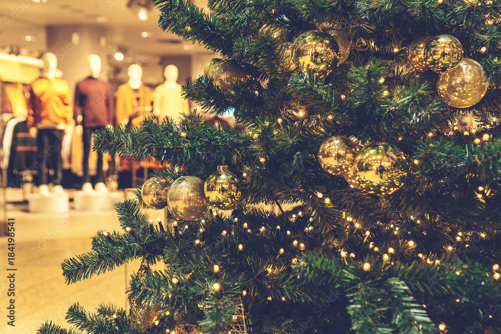 Fototapeta premium christmas tree in a mall with shopping clothes in the background