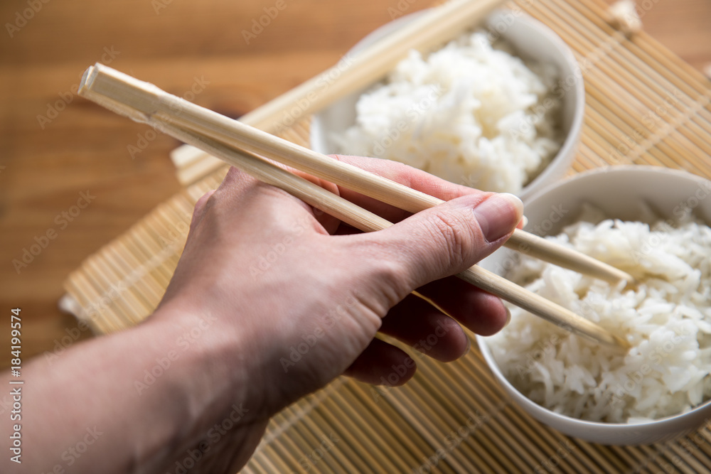 Frau isst Basmati Reis mit Stäbchen aus Schale Stock-Foto | Adobe Stock