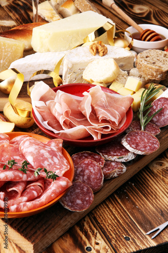 assorted cheese,meats and bread on wooden background