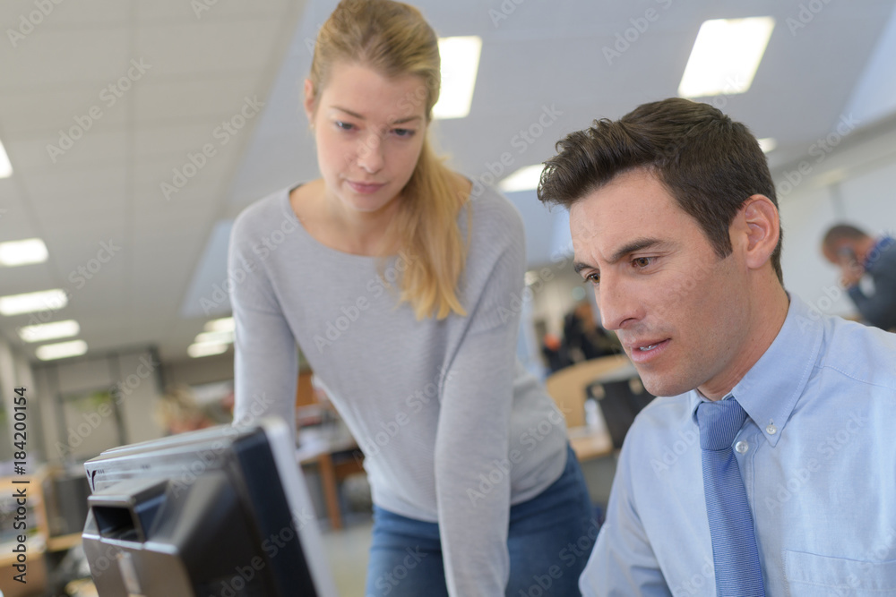 Woman looking over colleagues shoulder Woman looking over colleagues shoulder
