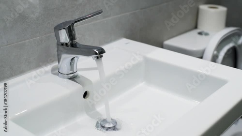Home water faucet closeup, flow open spilling water into the drain