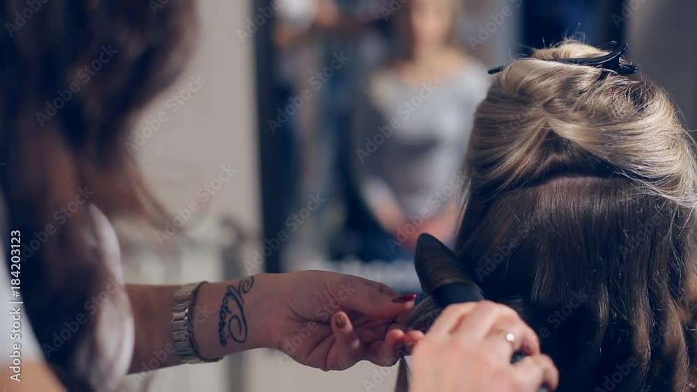 Professional hairdresser doing hairstyle with bun and curls for beautiful healthy hair Professional hairdresser doing hairstyle with bun and curls for beautiful healthy hair