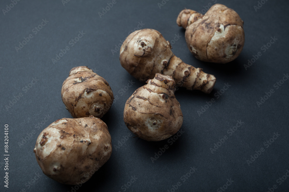 The tubers of raw Jerusalem artichoke are isolated on a black background. The tubers of raw Jerusalem artichoke are isolated on a black background.