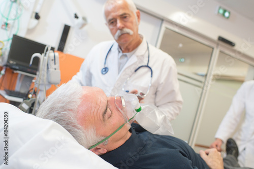 doctor examining his patient wearing oxygen mask