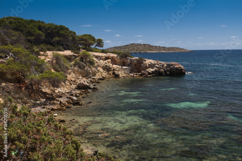 Rocky beach in Ibiza. View of the fishing garage and people photo