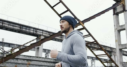 Wallpaper Mural Close up of the sporty handsome man in a cap jogging in the abandoned industrial district on the foggy day. Outside Torontodigital.ca