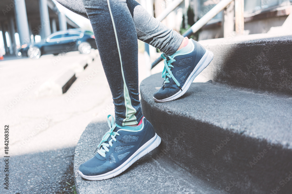 Close-up of sport sneakers on woman's foots steping on stairs after jogging.  Sport tight clothes. Stock Photo | Adobe Stock
