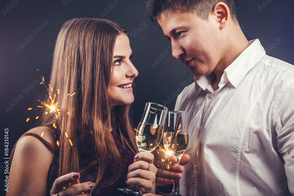 Couple celebrating New Year's eve drinking champagne and lighting up sparklers Couple celebrating New Year's eve drinking champagne and lighting up sparklers