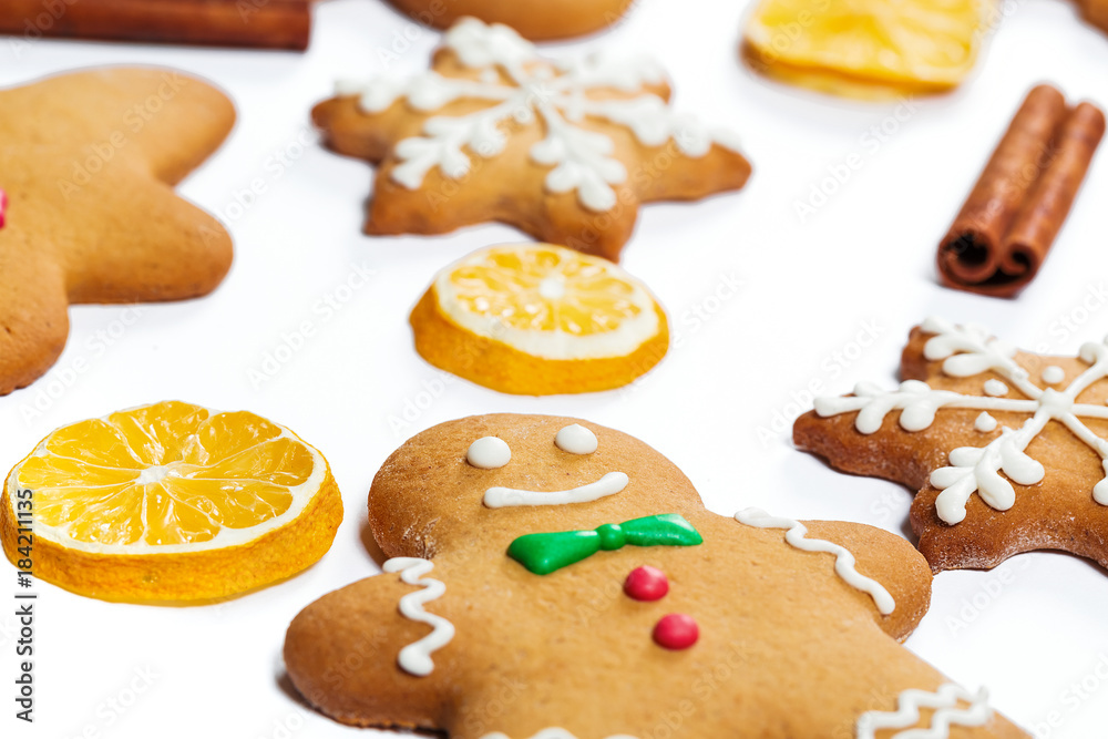 Fototapeta premium Christmas gingerbread men and snowflakes with lemon and cinnamon sticks on white background. A symbol of winter and new year holidays.