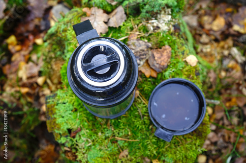A thermos with a cup of tee in forest.