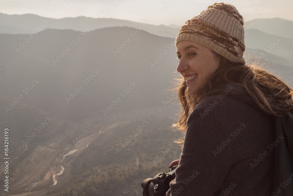 Woman on top of the mountain of cap in the cold watching happily the beautiful landscape of the wild nature around her
