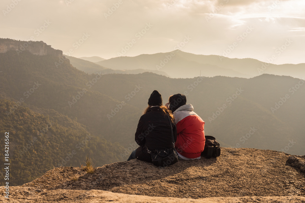 Fototapeta premium Couple sitting on high mountain peak watching the beautiful and surreal wilderness landscape in front of you in Siurana
