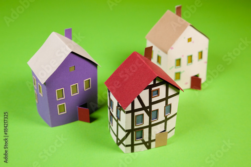 Three paper houses on a green background