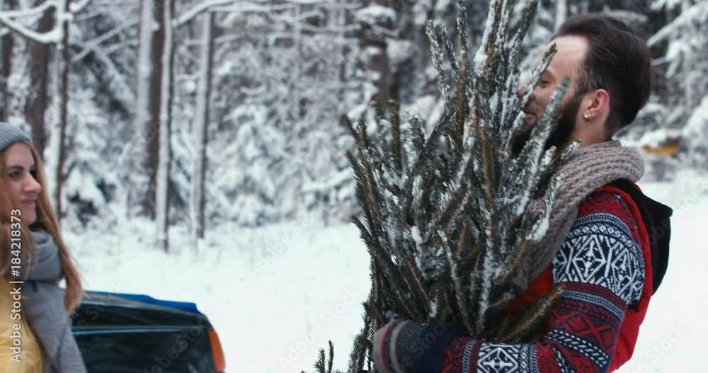 Girlfriend tying her boyfriend to a Christmas tree Christmas tree in the forest