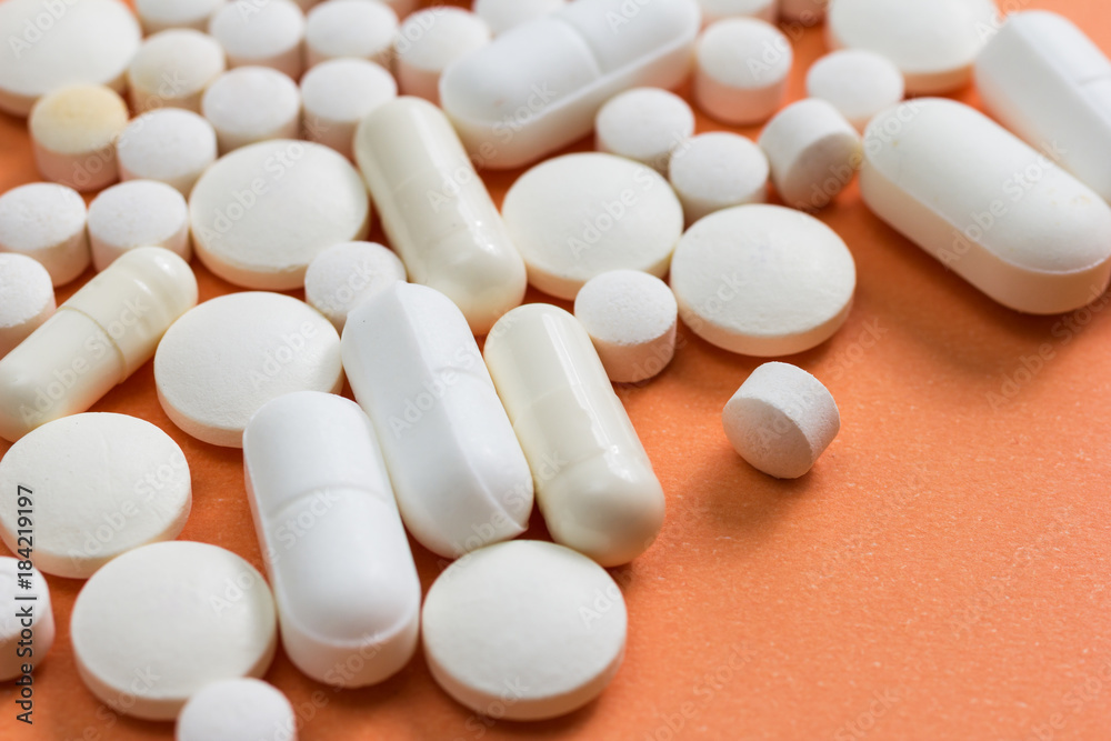 Heap of white capsules on orange background. Heap of white capsules on orange background.