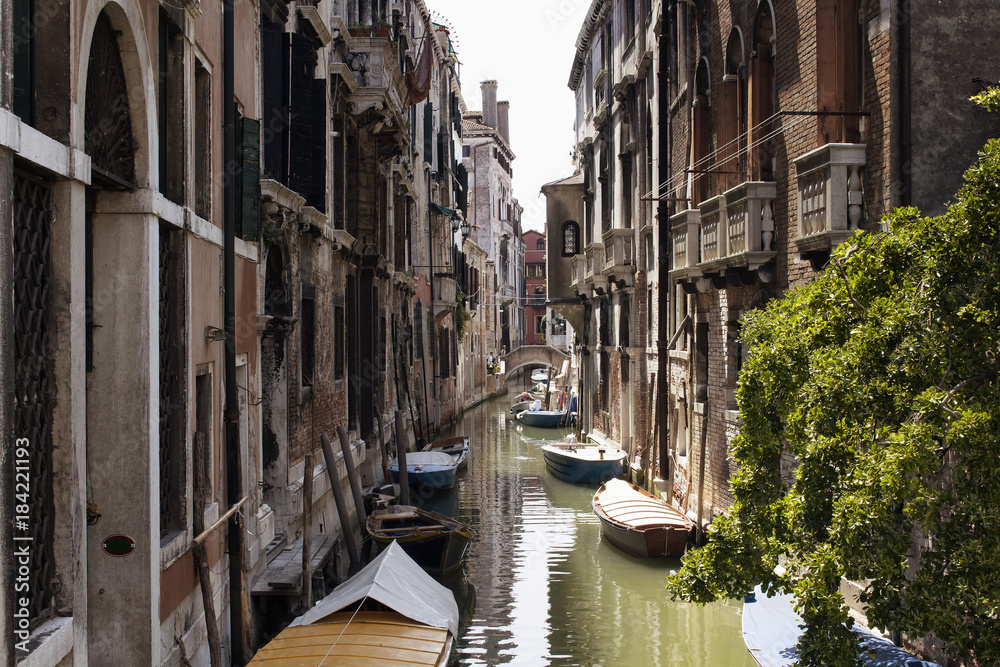 View of boats on canal and old, typical, historical buildings in Venice / Italy.