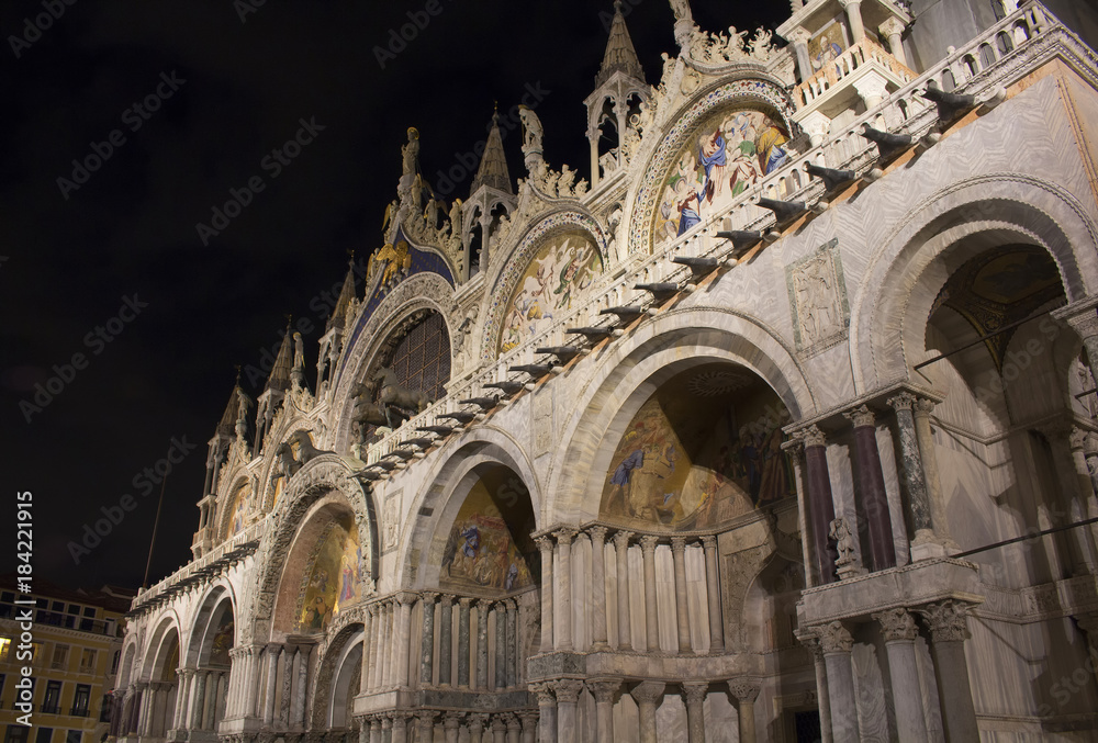 Facade view of Saint Mark's Basilica (San Marco) at night in Venice / Italy. Iconic cathedral with a cavernous gilded interior, myriad mosaics & an on-site museum.