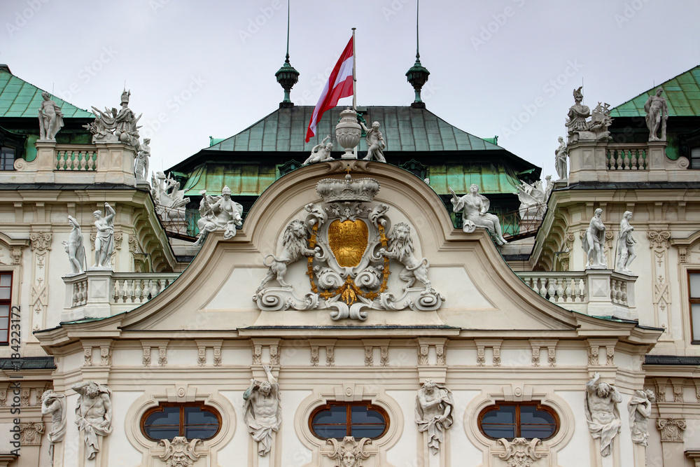 Closeup of facade over entrance and roof of Baroque style Belvedere Palace the former residence for Prince Eugene of Savoy with coat of arms and Austrian flag, Vienna, capital city of Austria, Europe