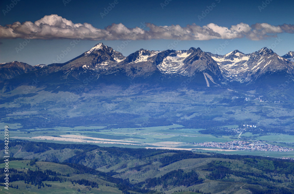 Sunny snowy peaks of High Tatras, Slovakia Europe, under fluffy white  clouds in spring with pyramid