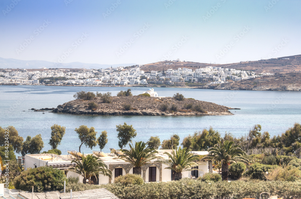 View over a bay with an island and a typical village on Paros, one of the Cyclade islands in Greece
