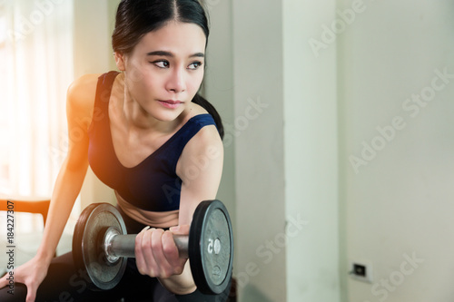 asian strong woman fit and firm healthy concept lifting dumbbell at gym