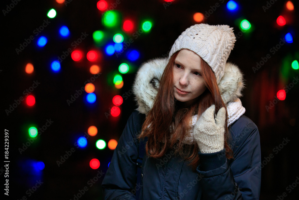 red head young woman in winter clothes on background of xmas garland on night street red head young woman in winter clothes on background of xmas garland on night street