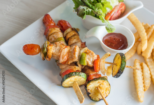 Tasty delicious pork/chicken skewer sticks - grilled pork/chicken kebab with red and green pepper with french fried and vegetable salad on whith plate