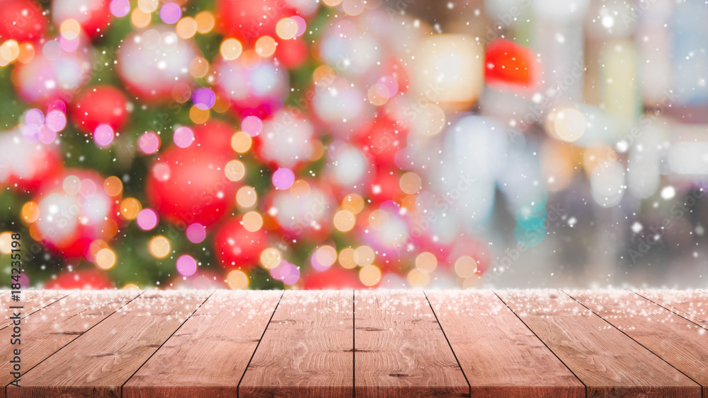 Wood table top on blur with bokeh Christmas tree background with snowfall - can be used for display or montage your products.