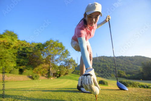 woman golf player put a golf ball onto wooden tees on the tees off, golf ball ready to hit after to the fairway ahead