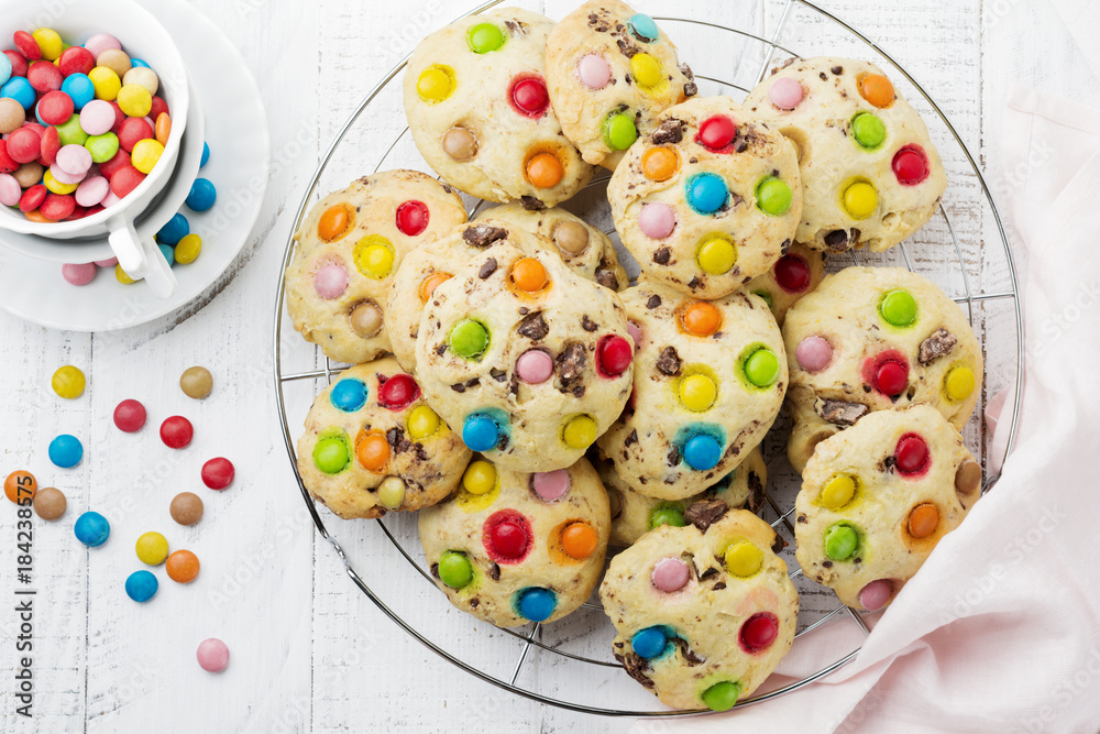 Children's cookies with colorful chocolate sweets in sugar glaze on white wooden background. Selective focus. Top view. Place for text. Children's cookies with colorful chocolate sweets in sugar glaze on white wooden background. Selective focus. Top view. Place for text.