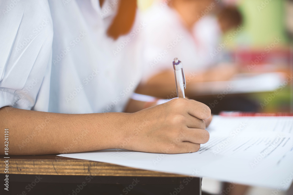 Closeup to hand of student holding pen and taking exam in classroom with stress for education test . Closeup to hand of student holding pen and taking exam in classroom with stress for education test .