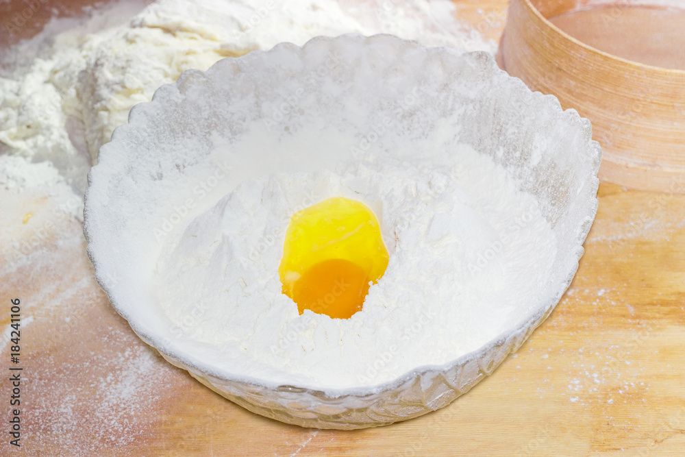 Bowl with flour and broken egg on the table Bowl with flour and broken egg on the table